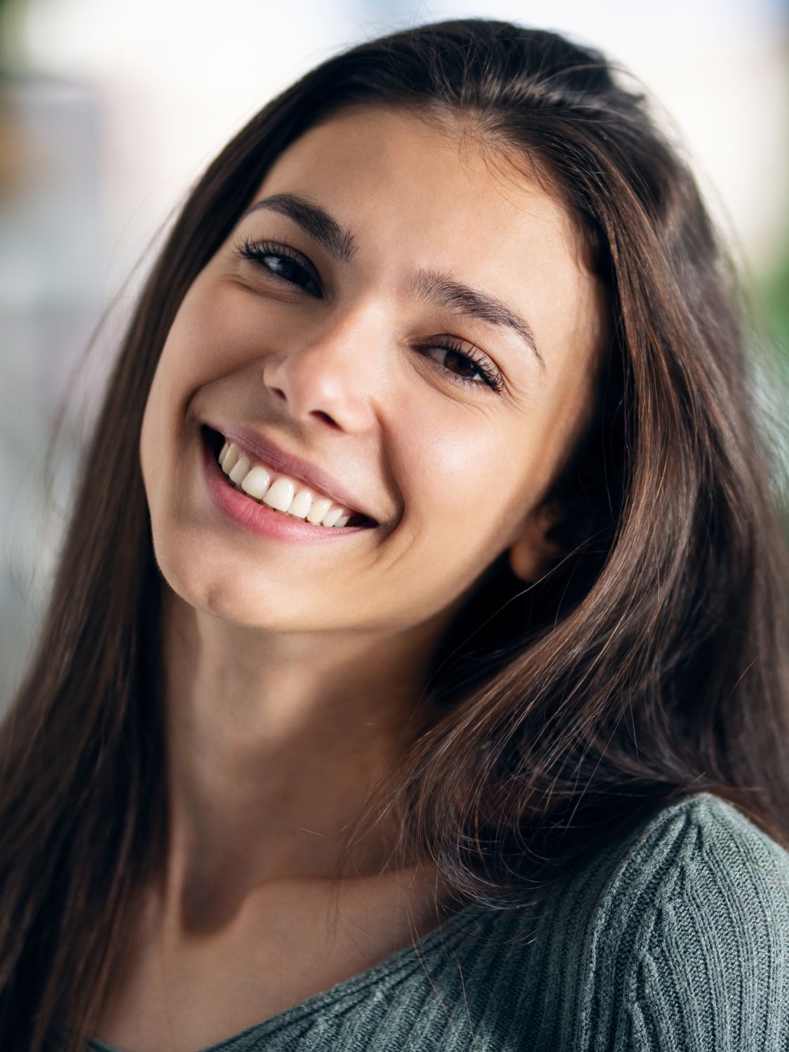 Smiling woman with wavy blonde hair indoors.