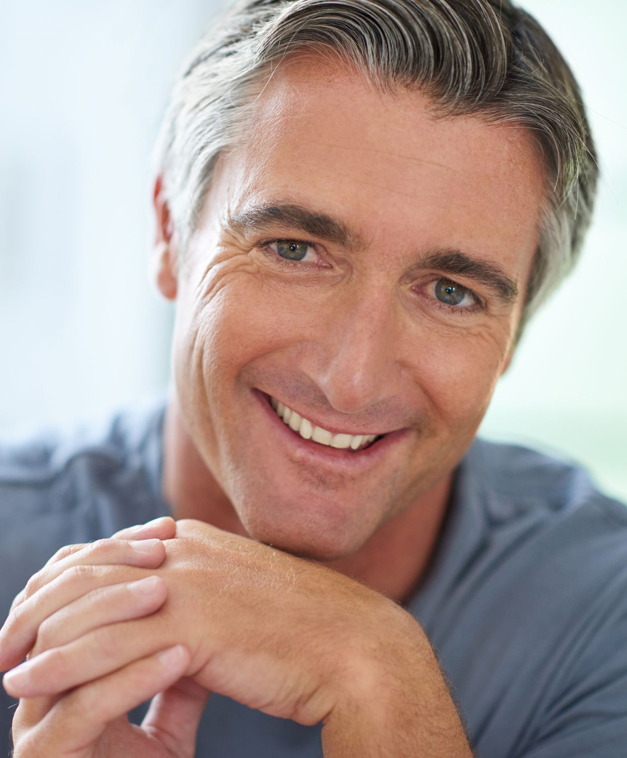 Smiling man resting hands on chin.