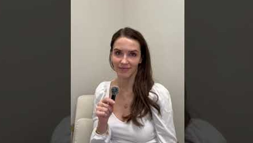 Woman holding a microphone in a light setting.